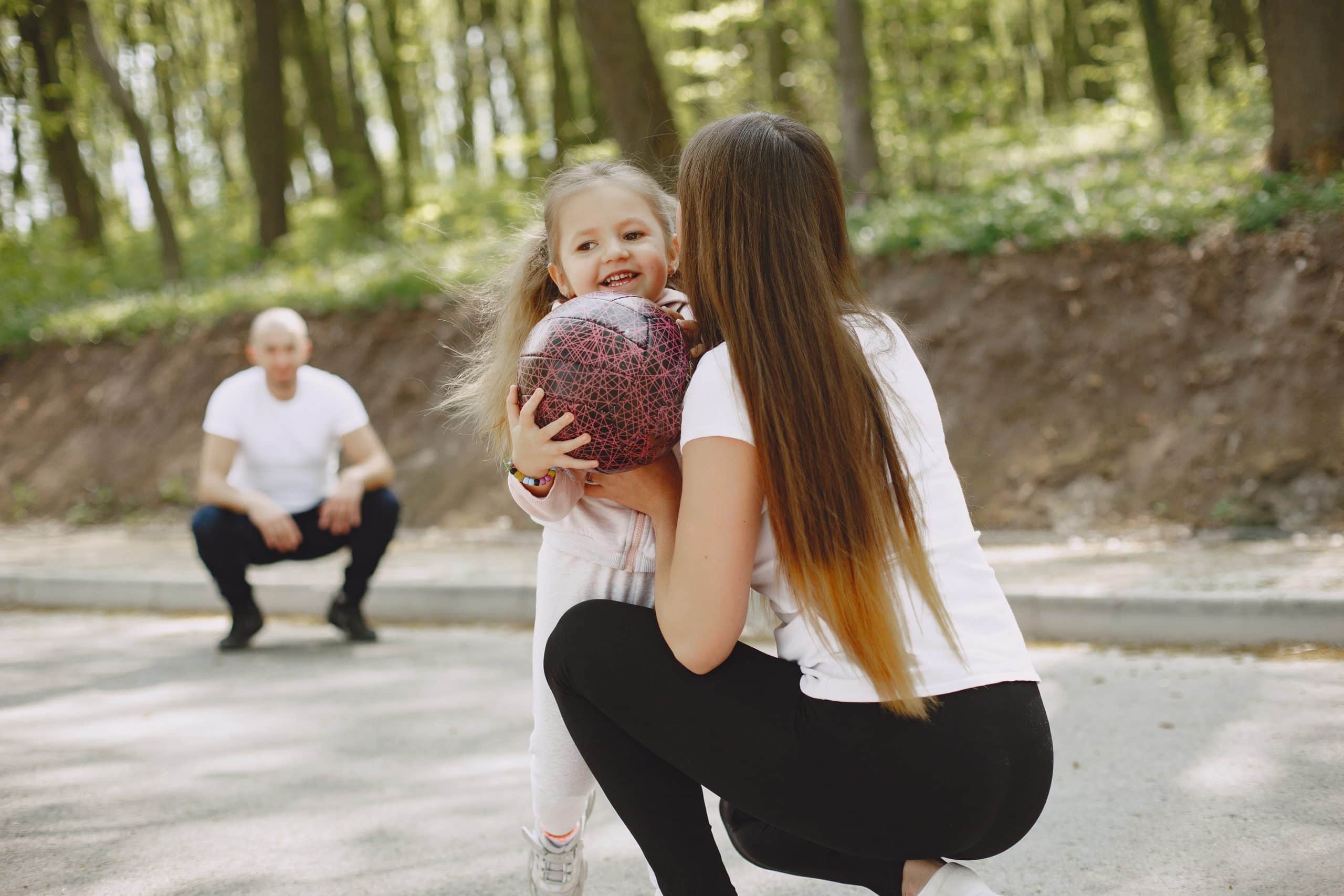 Family in a summer forest. Woman and man in a white t-shirts. Daughter with parents.